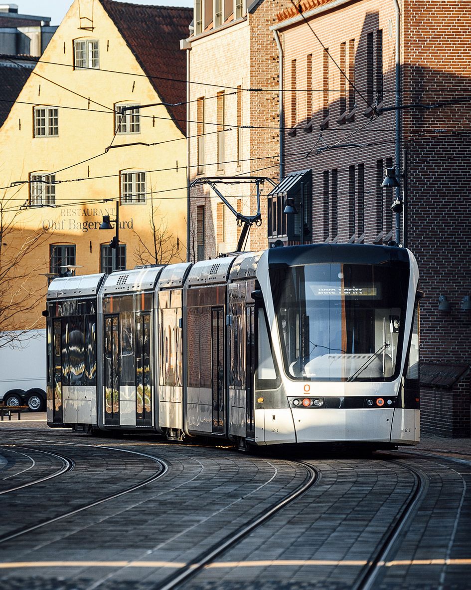 Modern tram travelling along curved tracks in an urban setting.